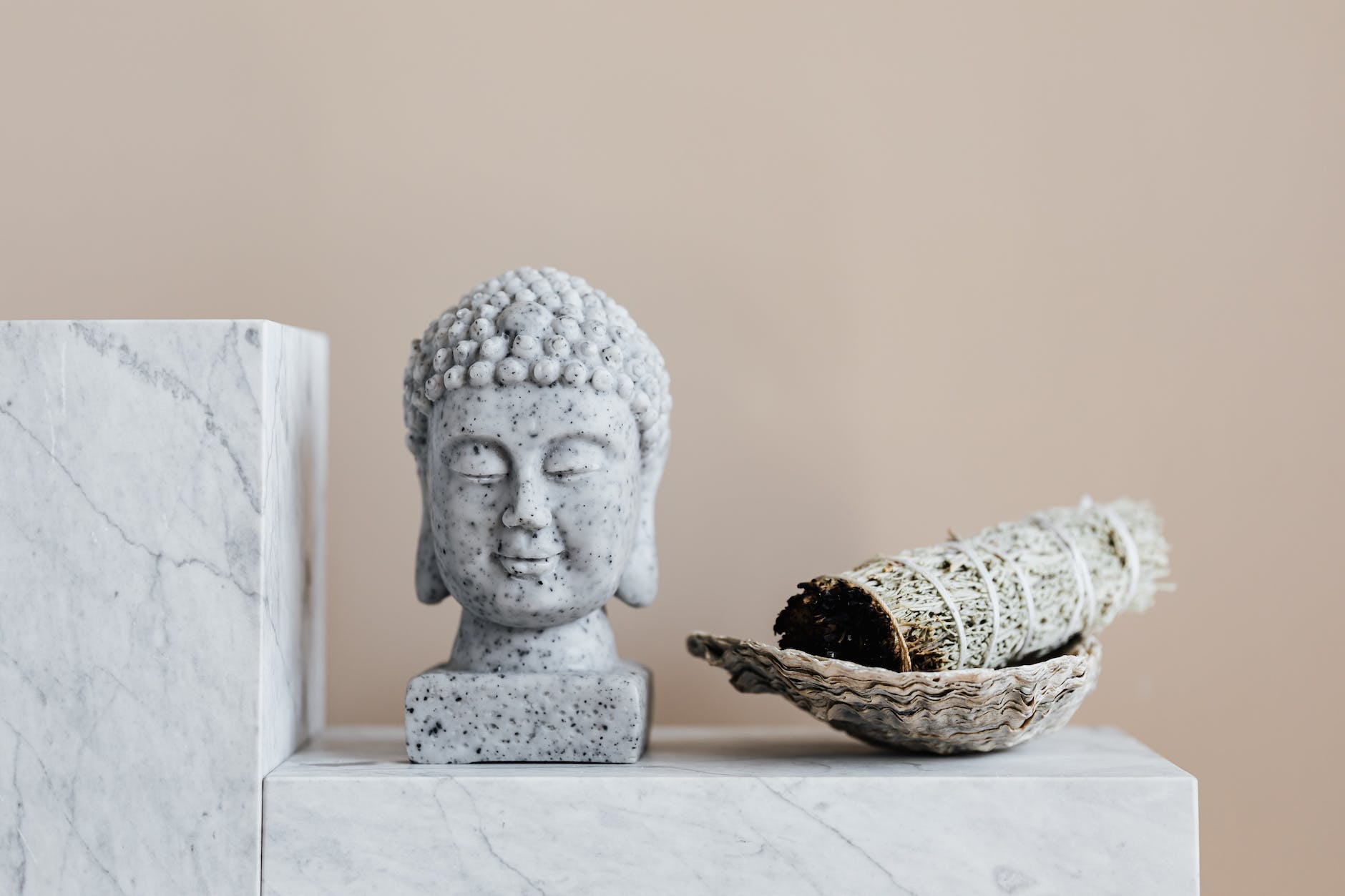 stone buddha and sage incense bundle in bowl on marble shelf