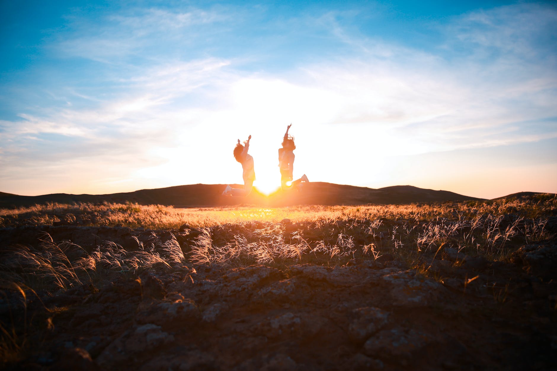 two women jumping on plant field